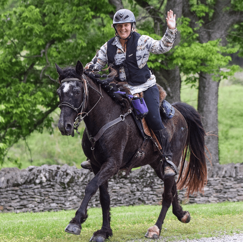 Rider wearing helmet waving on galloping horse