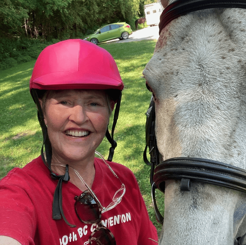 Smiling woman in pink helmet with horse